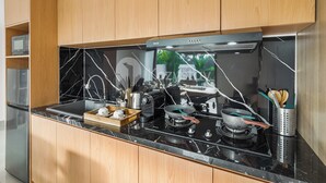 Una cocina moderna con armarios de madera, encimera negra y electrodomésticos de acero inoxidable, incluyendo una estufa y un microondas.