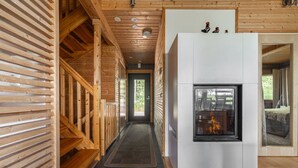 A wooden interior with a fireplace, a bench, and a view through a door.
