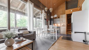 A modern kitchen with wooden beams, a dining area with white chairs, and a large window with curtains.