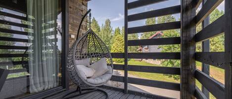 Eine Holzterrasse mit einer Hängematte und Blick auf ein Haus im Hintergrund.