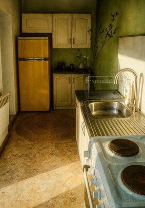 Een koelkast, een oven, een kookplaat, kookgerei, borden en bestek