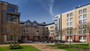 A modern apartment complex with multiple buildings, a central courtyard with benches, and well-maintained landscaping. - For Students Only - Modern Rooms in York (York)