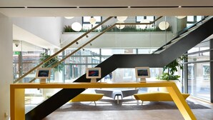 A modern interior with a staircase, glass walls, and two digital kiosks on a yellow table. - For Students Only - Modern Rooms in York (York)