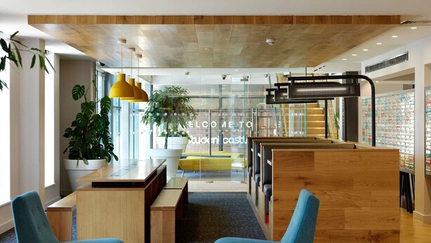 A modern lobby with wooden flooring, blue chairs, a reception desk, and a staircase. - For Students Only - Modern Rooms in York (York)