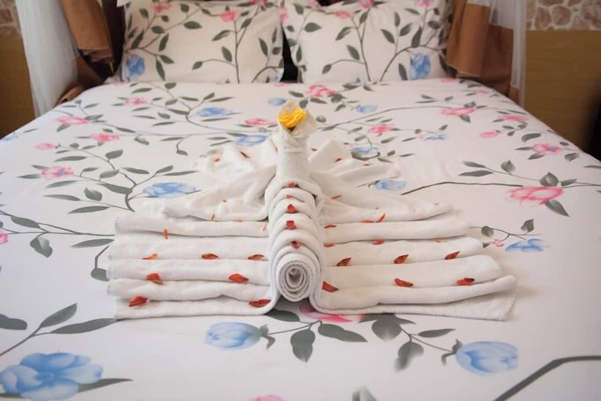 Un letto rifatto con uno splendido copriletto floreale e un'elegante disposizione di asciugamani al centro.