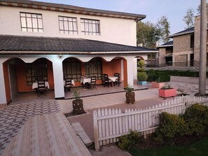 A building with a covered patio area, multiple tables and chairs, and a white picket fence.
