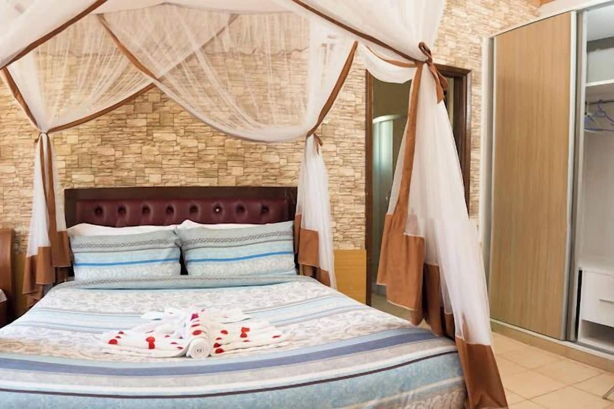 Camera da letto con parete in pietra, testiera capitonata e letto a baldacchino.