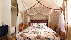 A bedroom with a bed under a canopy, a stone wall, and a wardrobe. - Royal Gardens Getaway (Ol Kalou)