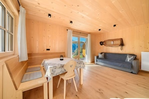 Un intérieur en bois comprenant une table à manger, des chaises, un canapé et une fenêtre avec des rideaux.