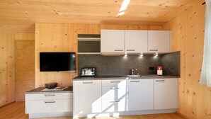 Eine kompakte Küche mit Holzwänden, einem Flachbildfernseher, weißen Schränken und einer Arbeitsplatte mit einem Toaster.