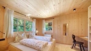 Ein Zimmer aus Holz mit einem Bett, einem Schreibtisch und einem Stuhl.