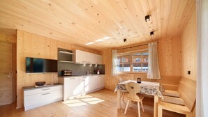 Ein Holzblockhaus mit Küche, Essbereich und einem Fenster mit Vorhängen.
