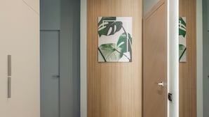 Un pasillo con paredes de madera, un banco tapizado de color verde y una puerta con espejo.