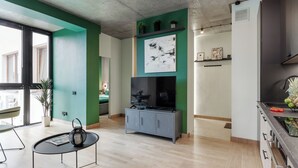 Un salón moderno con un mueble gris, un televisor de pantalla plana y una pared de acento verde.