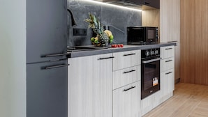 Una cocina moderna con armarios oscuros, una encimera de madera, un microondas y un horno empotrado.