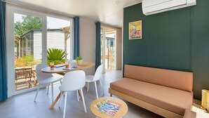 Une pièce moderne comprenant un canapé, une table à manger avec des chaises, une petite table ronde avec des magazines et une grande fenêtre avec des rideaux.