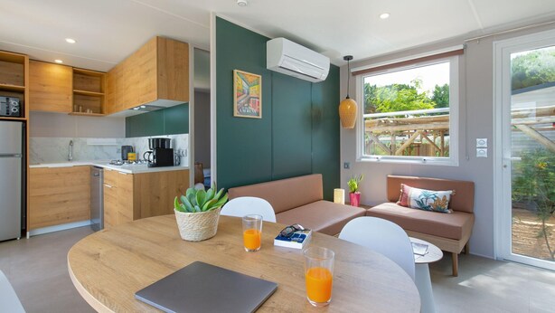 Une cuisine moderne avec des meubles en bois, un coin repas doté d’une table ronde et un espace détente avec un banc.