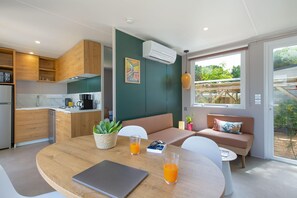 Eine moderne Küche mit Holzausstattung, ein Essbereich mit rundem Tisch und eine Sitzgruppe mit einer Bank.