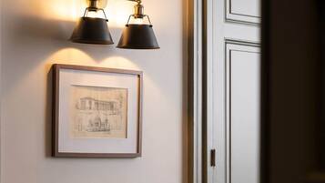 Ein Flur mit einem gerahmten architektonischen Entwurf an der Wand, einer Tür mit Griff und einer Wandleuchte mit zwei Lampen.