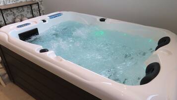 A hot tub with water jets, a control panel, and a wooden shelf.