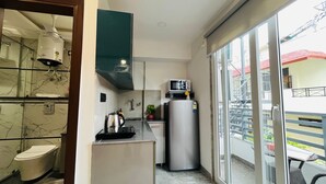 A compact kitchen with a microwave, kettle, and a refrigerator. - Stay near - Hotel near me Gurgaon (Gurugram)