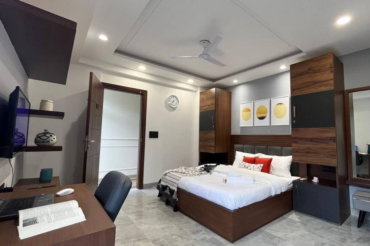 Un dormitorio moderno con cama, escritorio, silla y un espejo grande.
