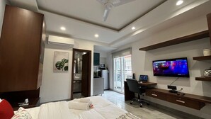 A hotel room with a bed, a desk with a computer, a TV, and a wardrobe. - Stay near - Hotel near me Gurgaon (Gurugram)