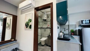 A compact kitchen with a microwave, kettle, and a small sink. - Stay near - Hotel near me Gurgaon (Gurugram)