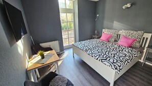 Quarto moderno com uma cama grande, uma escrivaninha e uma cadeira.