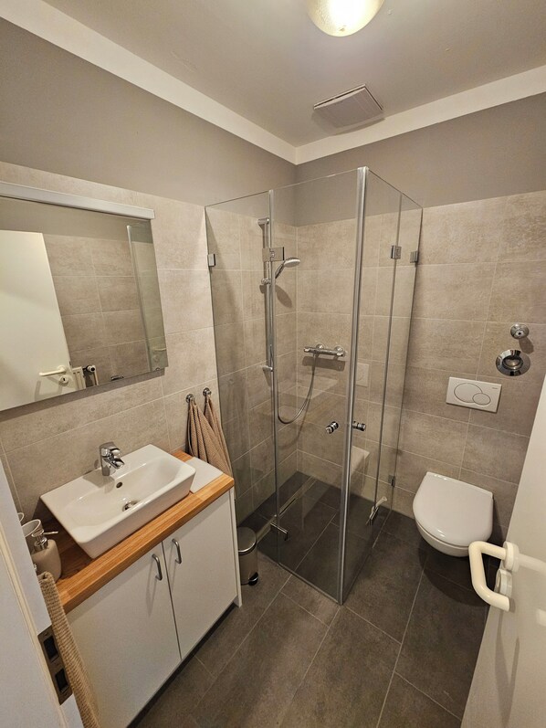 Une salle de bain moderne avec une douche à parois de verre, un lavabo blanc et des toilettes.