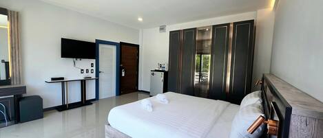 A hotel room with a large bed, a desk, a wardrobe, and a TV mounted on the wall.