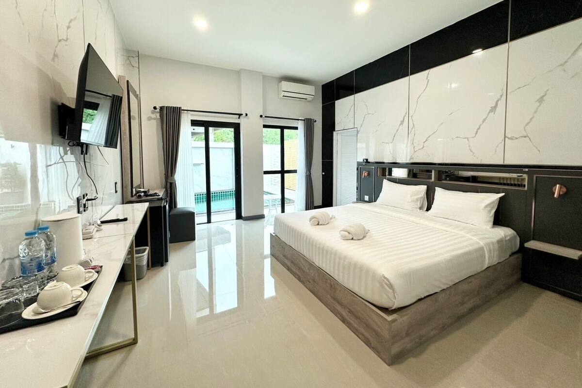 Une chambre d’hôtel moderne dotée d’un grand lit, d’une télévision à écran plat, d’un bureau avec des articles de toilette et d’un balcon offrant une vue agréable.