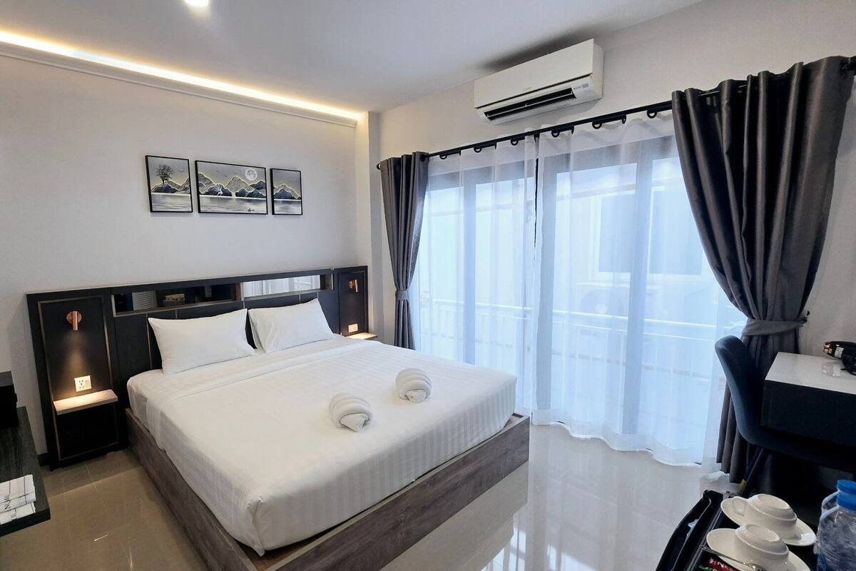 Une chambre d’hôtel avec un grand lit, un bureau, une chaise et une fenêtre avec des rideaux.