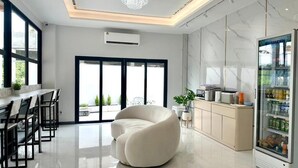 A modern kitchen with a marble backsplash, a built-in refrigerator, and a dining area with a white chair and a table. - Smile Boutique at Saiyuan (Rawai)