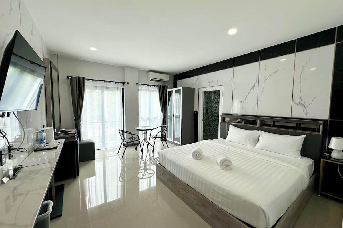 Une chambre d’hôtel moderne dotée d’un grand lit, d’un bureau avec un téléviseur à écran plat, d’une chaise et d’une petite table.