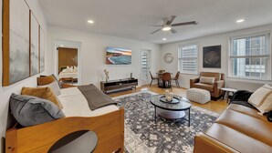 A modern living room with a bed, seating area, and a dining table.