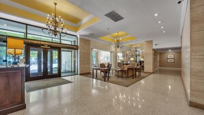 A spacious lobby with a reception desk, a chandelier, and a seating area with a coffee table and chairs.