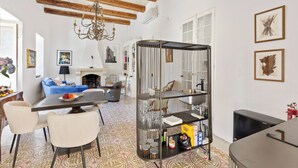 Amplia sala de estar con una mesa de comedor, sillas, un sofá azul y un estante decorativo de metal.