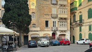 Una calle con coches aparcados y un edificio con un cartel que dice 'Mothercare'.