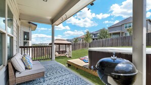 Un patio techado con una parrilla, mobiliario exterior y vistas del barrio.