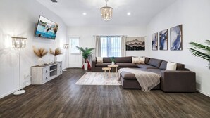 Una sala de estar moderna con un sofá modular, un televisor de pantalla plana y plantas decorativas.
