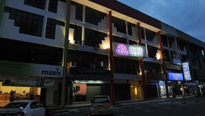 A hotel with a prominent sign, multiple floors, and various storefronts on the ground level. - MILANO HOTEL (Kluang)