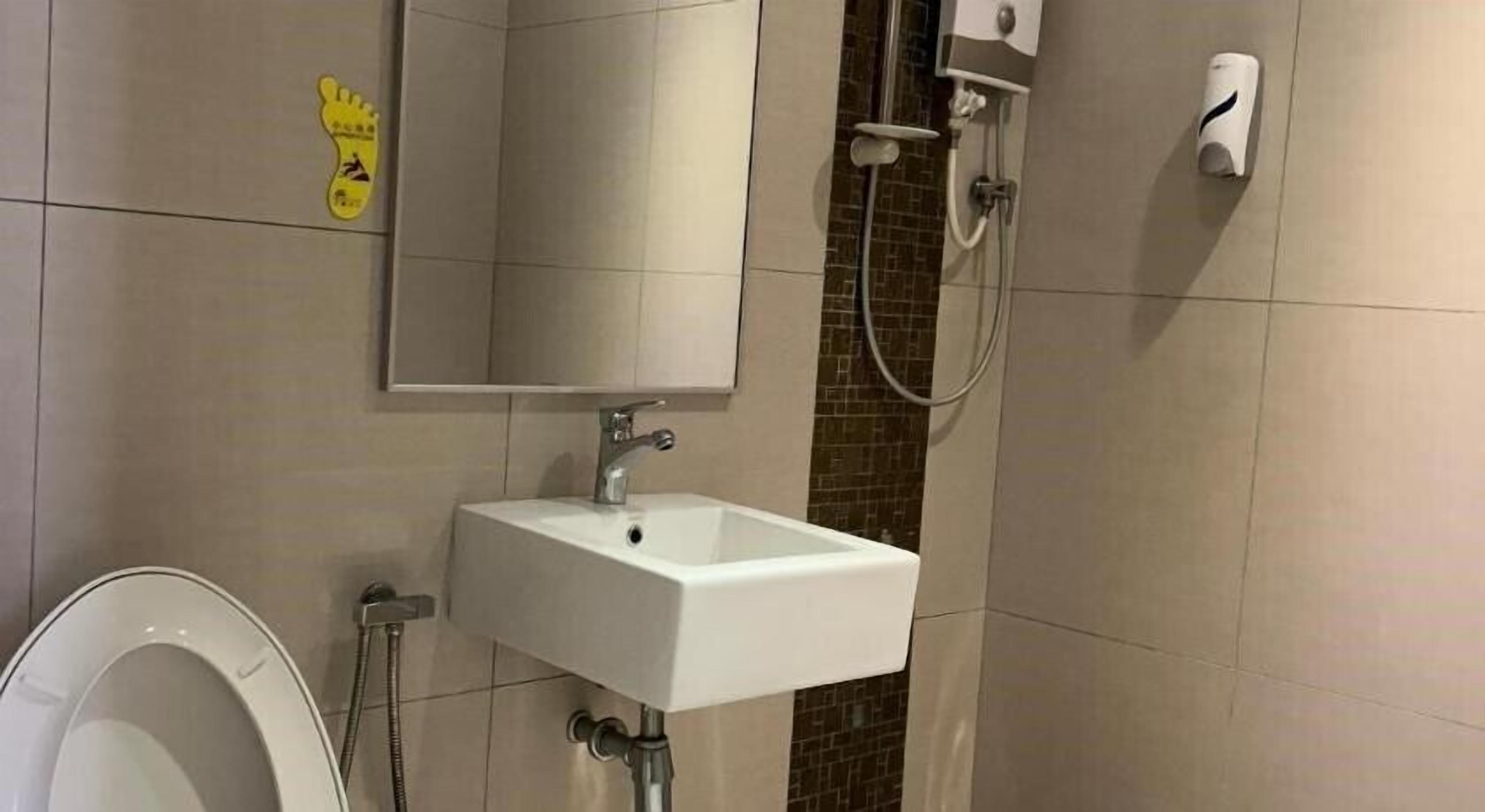 A bathroom with a white sink, a mirror, a toilet, and a shower area.