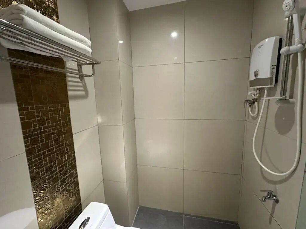 Un baño con ducha, toallero y retrete.