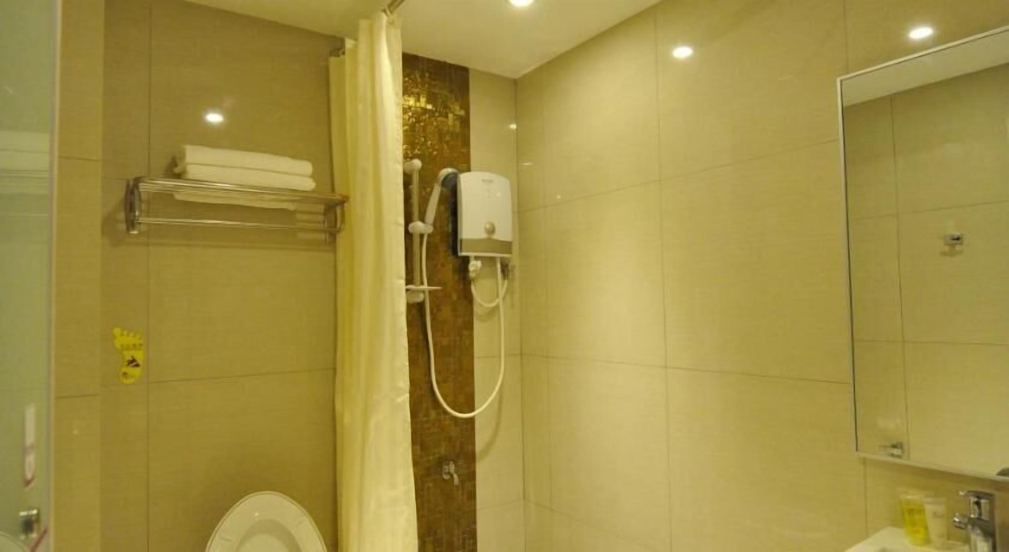 Ein Badezimmer mit Dusche, Toilette und Spiegel.