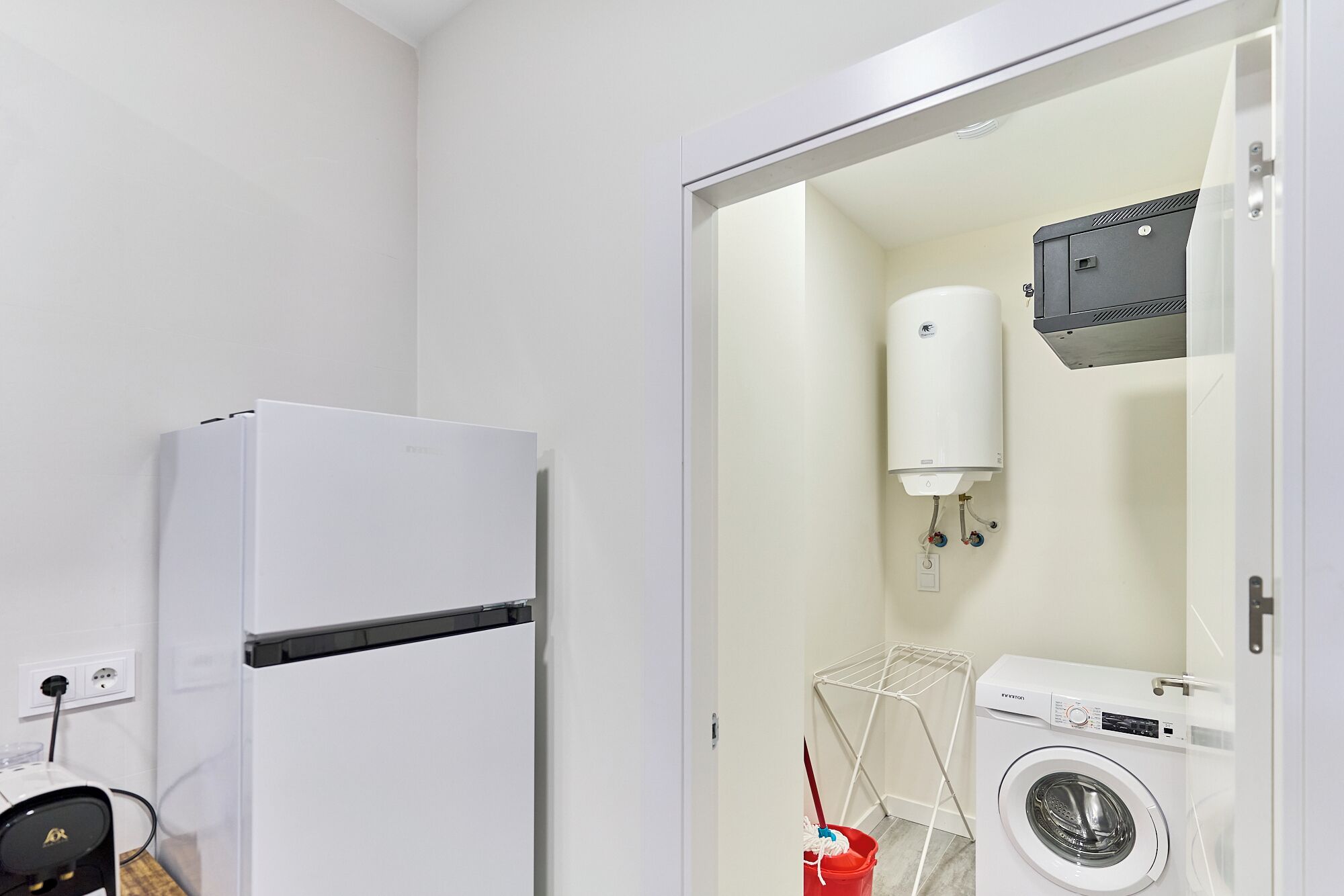 A modern bathroom with a white toilet, a white sink, a white washing machine, and a white heater.