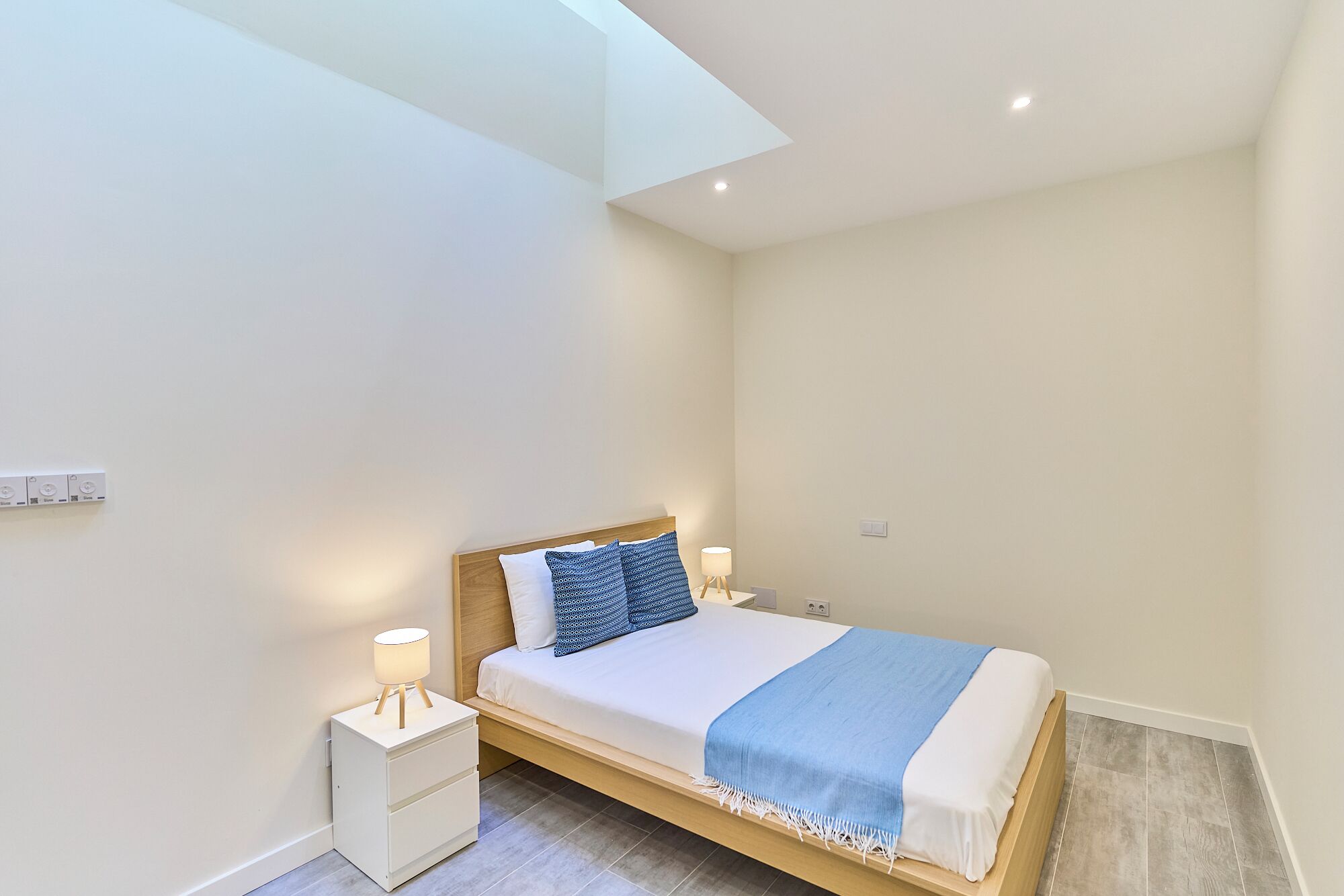 A bedroom with a bed, bedside tables, a lamp, and a ceiling light.