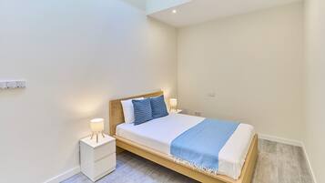 A bedroom with a bed, bedside tables, a lamp, and a ceiling light.