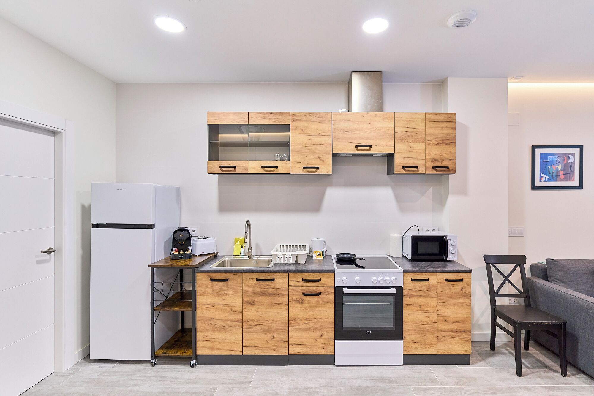 Une cuisine compacte avec des meubles en bois, un four encastré, un four à micro-ondes et une machine à café.