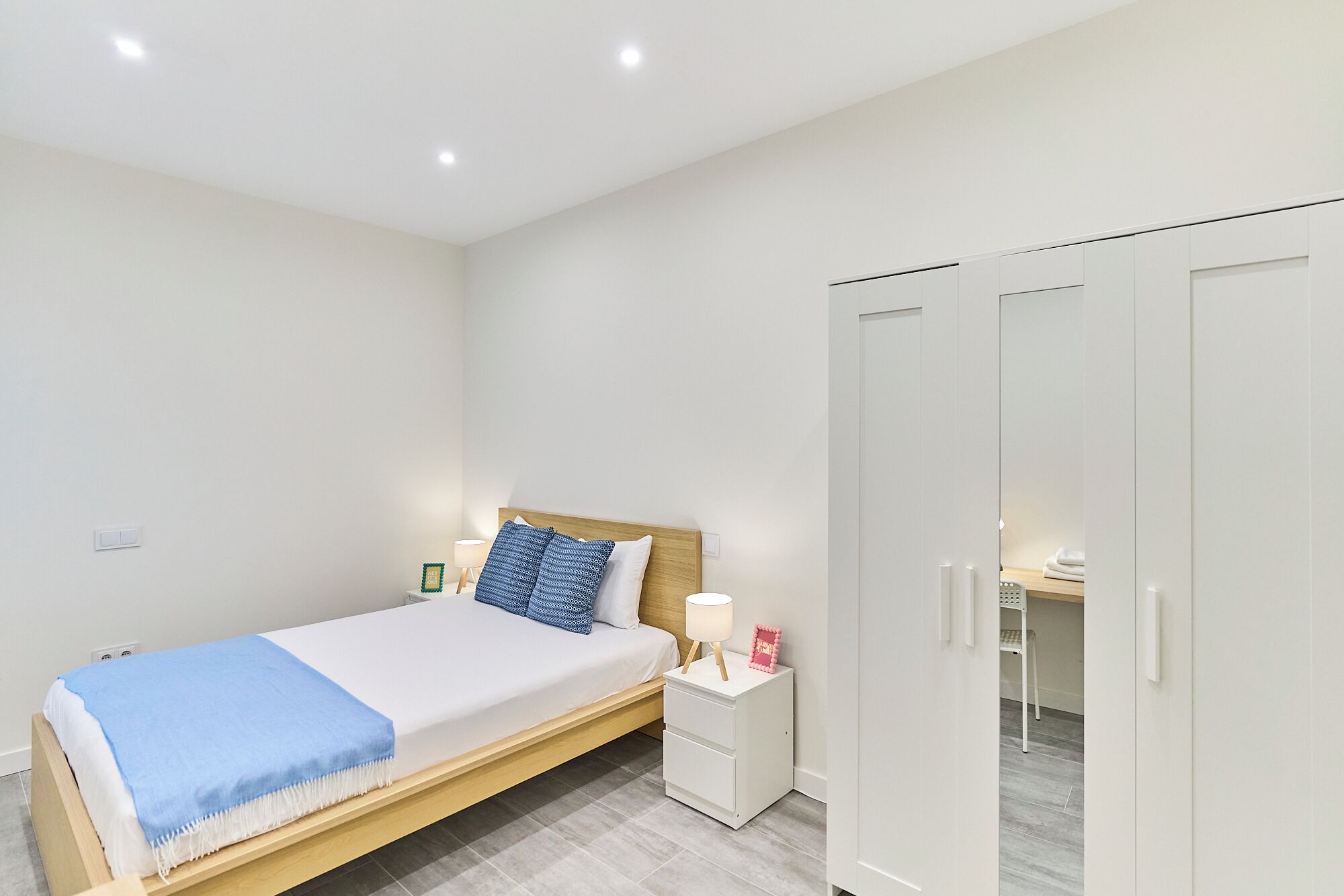 A bedroom with a bed, bedside table, lamp, and wardrobe.